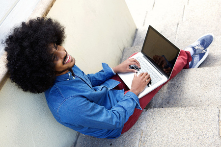 微笑年轻黑人使用的便携式计算机外