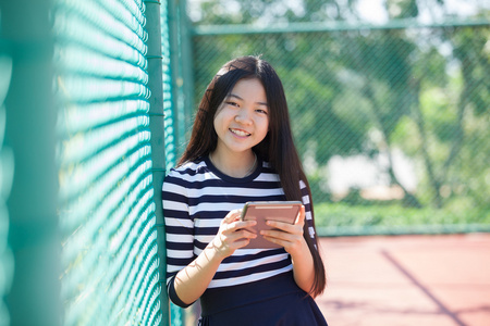 亚洲女孩和电脑平板露齿笑着用手指在手站