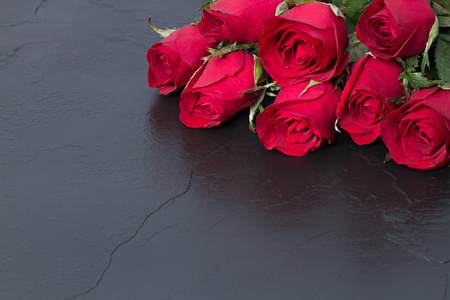 黑色的石头背景上的红玫瑰。情人节那天背景