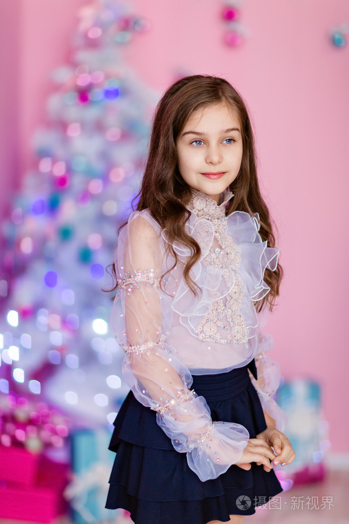 微笑着卷毛的年轻女孩,靠在一棵白色的圣诞树