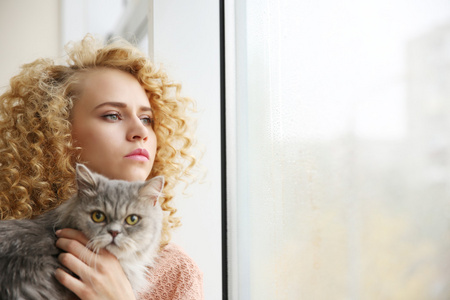 年轻女子和窗台上的猫