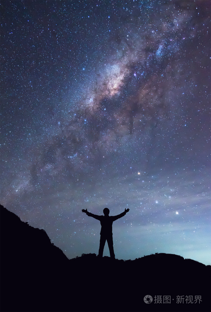 一个人站在银河星系传播手旁边