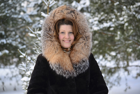 积极在冬季公园的毛皮大衣的中年女人