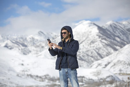 一个年轻的男子，在冬天天户外散步。年轻人以自拍照在雪地里享受在冬季的一天