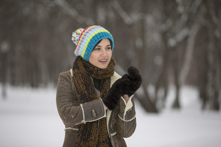 在严寒的冬季公园的美丽女孩。户外活动。纷飞的雪花