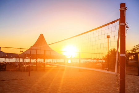在海滩上的一个排球网和日出 sillhouette