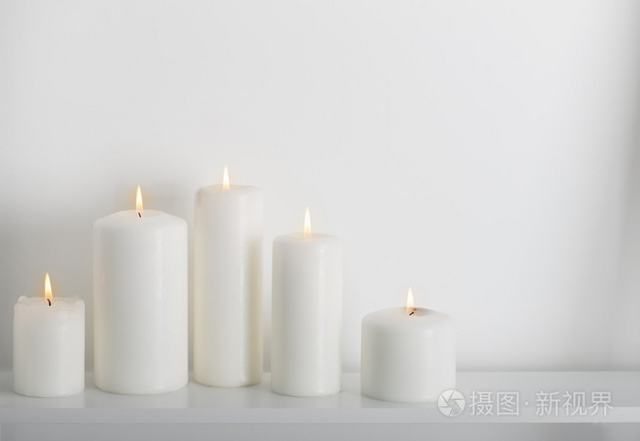 白色的蜡烛燃烧在一个白色的架子上