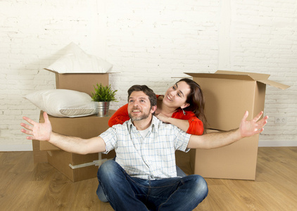 坐在地板一起庆祝搬进新平的房子或公寓的年轻快乐夫妇