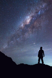 一个人是站在和在夜晚的天空上看到银河系