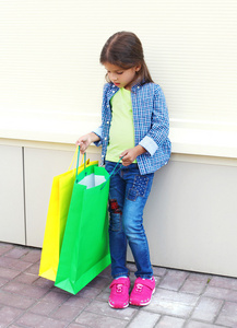 漂亮的小女孩孩子与购物在五颜六色的纸包