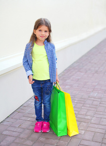 漂亮的小女孩孩子与购物纸袋走在