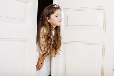 在家里穿裙子可爱的小女孩在家里,打开门衣着穿白色连衣裙,可爱牛奶