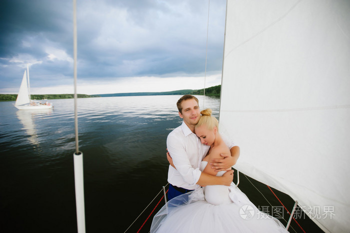 幸福的新娘和新郎在一艘游艇上拥抱