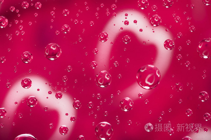 心反映中的小水滴.红色背景的玻璃上的水滴