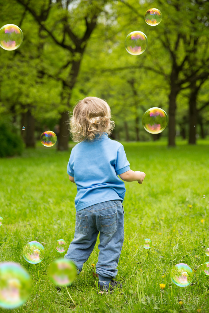 可爱的卷发婴儿带肥皂泡. 孩子们在玩跑步