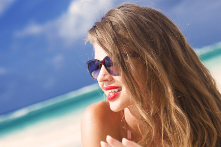 年轻女子与红红的嘴唇和条纹泳装在热带海滩