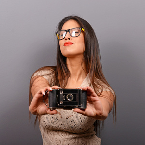 一个年轻的女人，灰色的背牵着复古相机的肖像