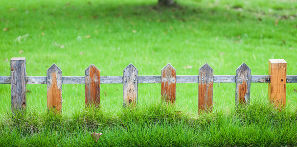 花园里的绿色草坪上的旧小栅栏照片