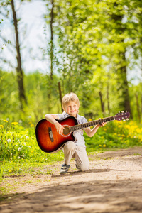 吉他在夏天公园里的小男孩