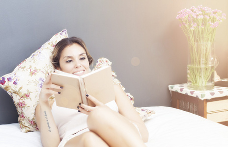 年轻漂亮的女人在床上读书图片
