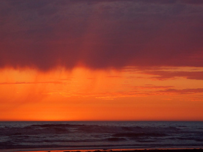 在海洋上的多云日落与前景中的波浪