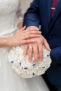 新婚夫妇与上不寻常的婚礼花束的戒指的手