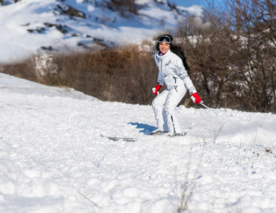 幸福的女人在阳光明媚的山坡上滑雪