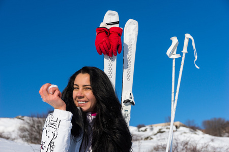 有滑雪板的年轻女子在山坡上吃苹果