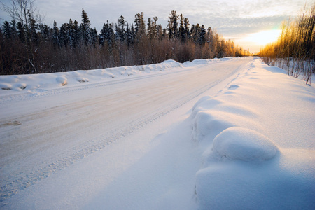 冬日白雪覆盖的道路上明亮的太阳日落