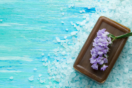 天然有机肥皂和海盐与蓝色木制的桌子上的花