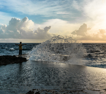 年轻男子站在一起举的手,在怒吼的大海照片