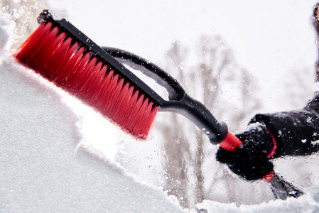 删除雪用画笔从汽车挡风玻璃在冬季的一天