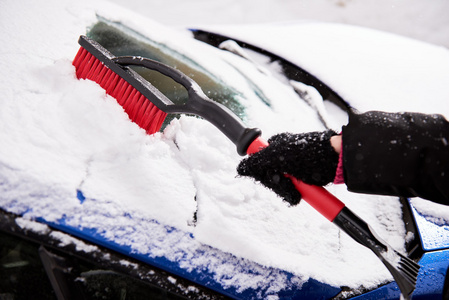 删除雪用画笔从汽车挡风玻璃在冬季的一天