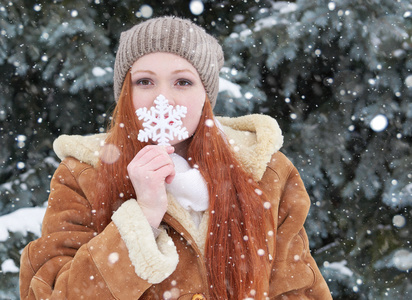 在冬天室外,下雪天气,显示大雪花玩具的女孩画像照片