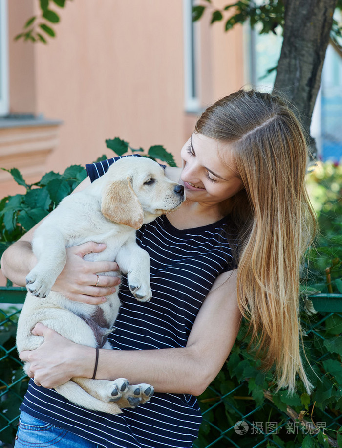 女人抱着小狗的犬种拉布拉多照片