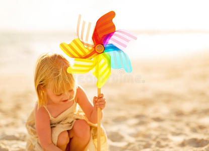 小女孩在沙滩上玩风车玩具
