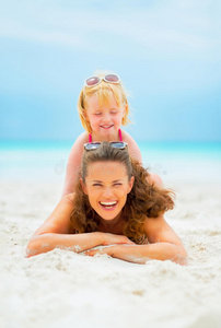 微笑的妈妈和小女孩在沙滩上玩耍