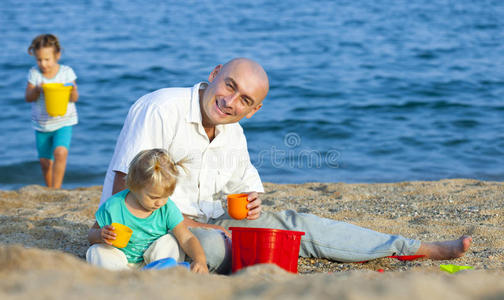女孩们在爸爸旁边玩沙子