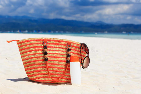 热带海滩上的包太阳眼镜和防晒霜