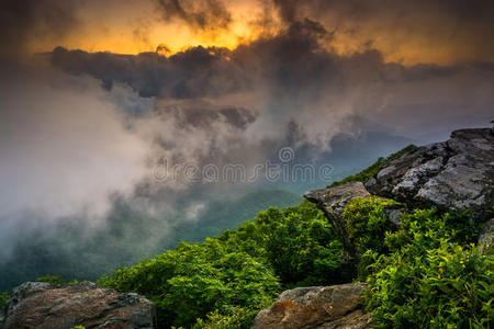 穿过雾霭的夕阳，从崎岖的尖顶上，在蓝色的山脊附近看到