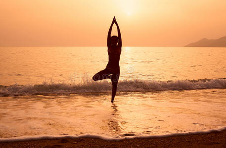 一个女孩在海滩上练习瑜伽的剪影