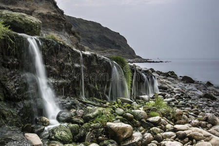 日出时大瀑布流到岩石海滩的景观图