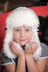 小女孩戴着白色毛皮帽子，手里拿着雪