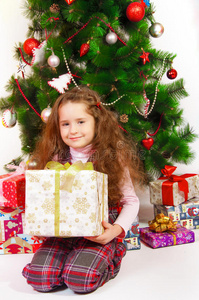 圣诞树旁拿着礼物的小女孩