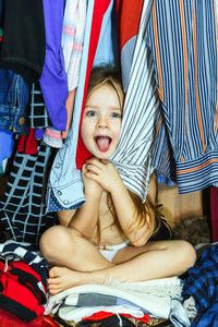 可爱的小女孩躲在衣柜里不让父母看见
