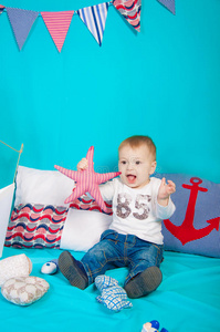 一个小男孩拿着玩具在海洋装饰的背景上