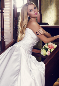 美丽的金发新娘，穿着优雅的婚纱和花束