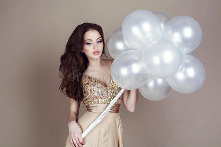美丽的黑发女子穿着豪华的礼服，手里拿着一个白色的气球