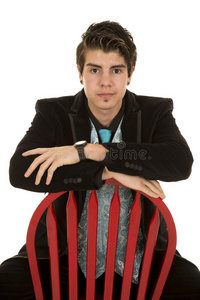 一个穿黑西装的男人正经地坐在红椅子上