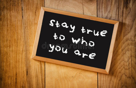 黑板的俯视图,上面写着"忠于你自己",背景为木质照片